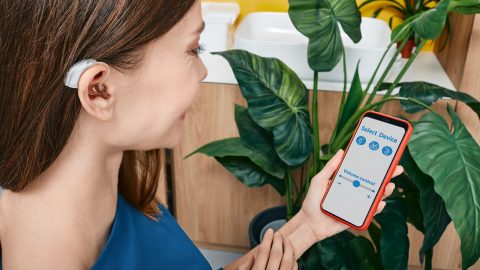 woman wearing hearing aid, using smartphone woman wearing hearing aid, using smartphone